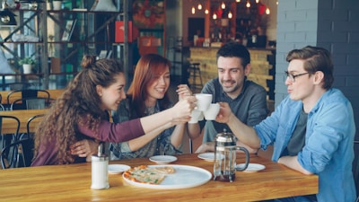 Friends celebrate with a coffee toast at a restaurant.