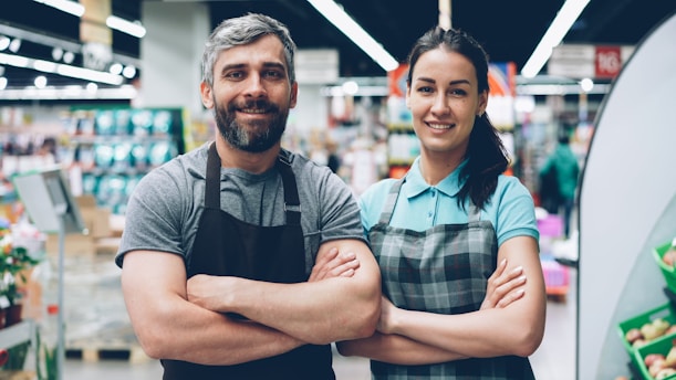 Two grocery store employees smiling at the camera.