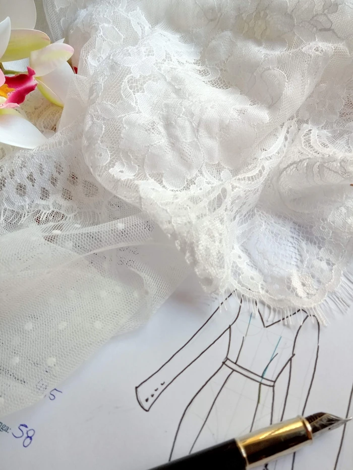 A hand-drawn bridal gown sketch laid out with delicate white lace