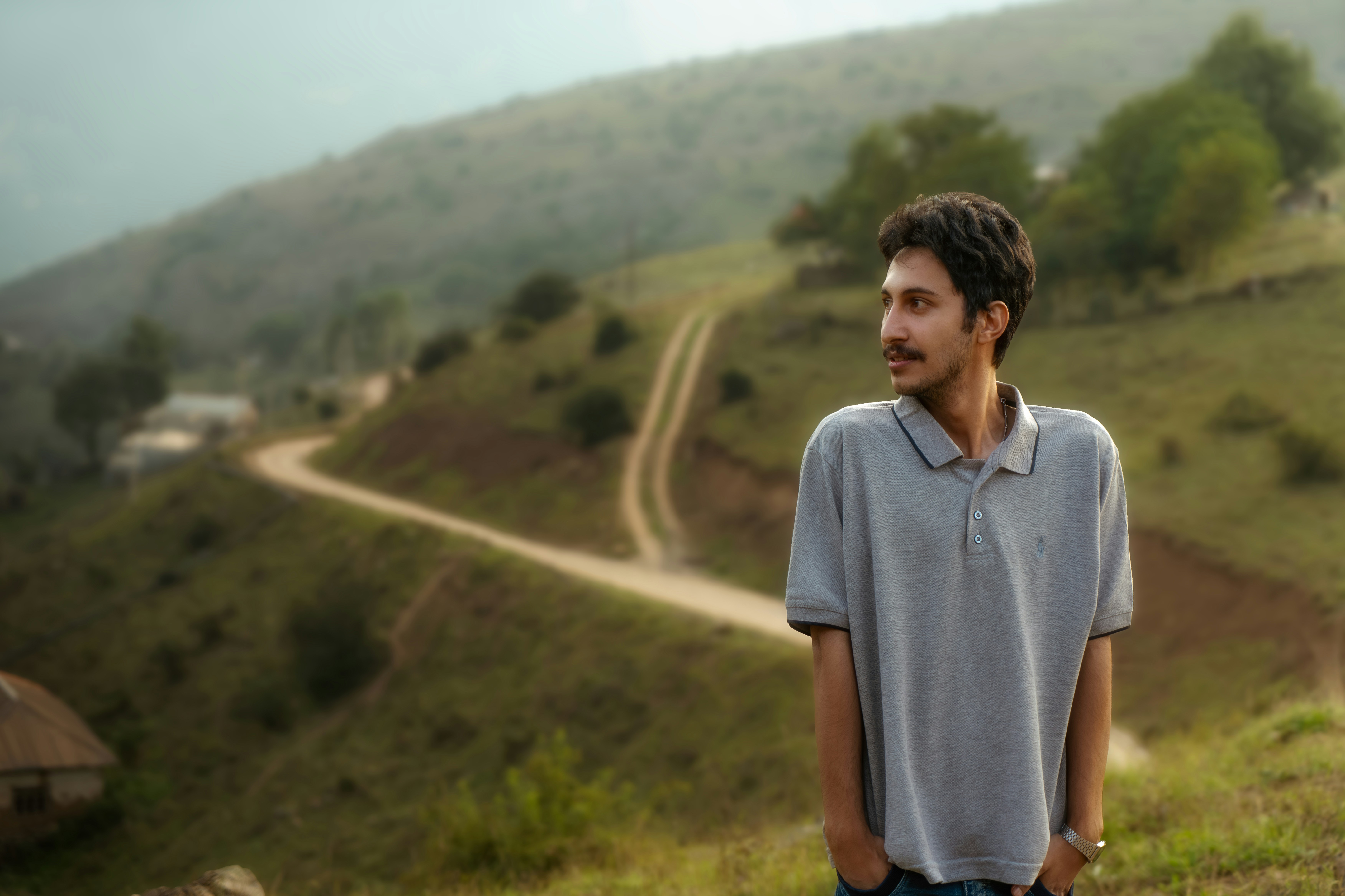 Man poses in front of a winding countryside road.