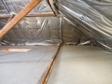 Inside of an attic with insulation and wood beams.