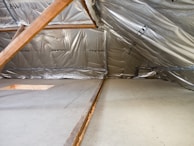 Inside of an attic with insulation and wood beams.