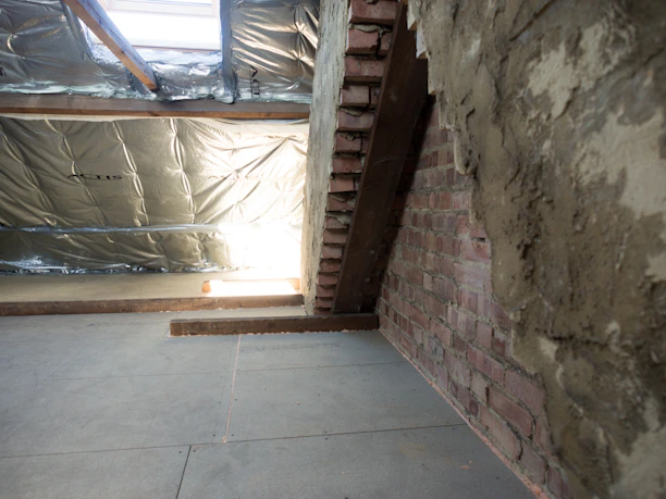 Inside of an unfinished attic with exposed brick.