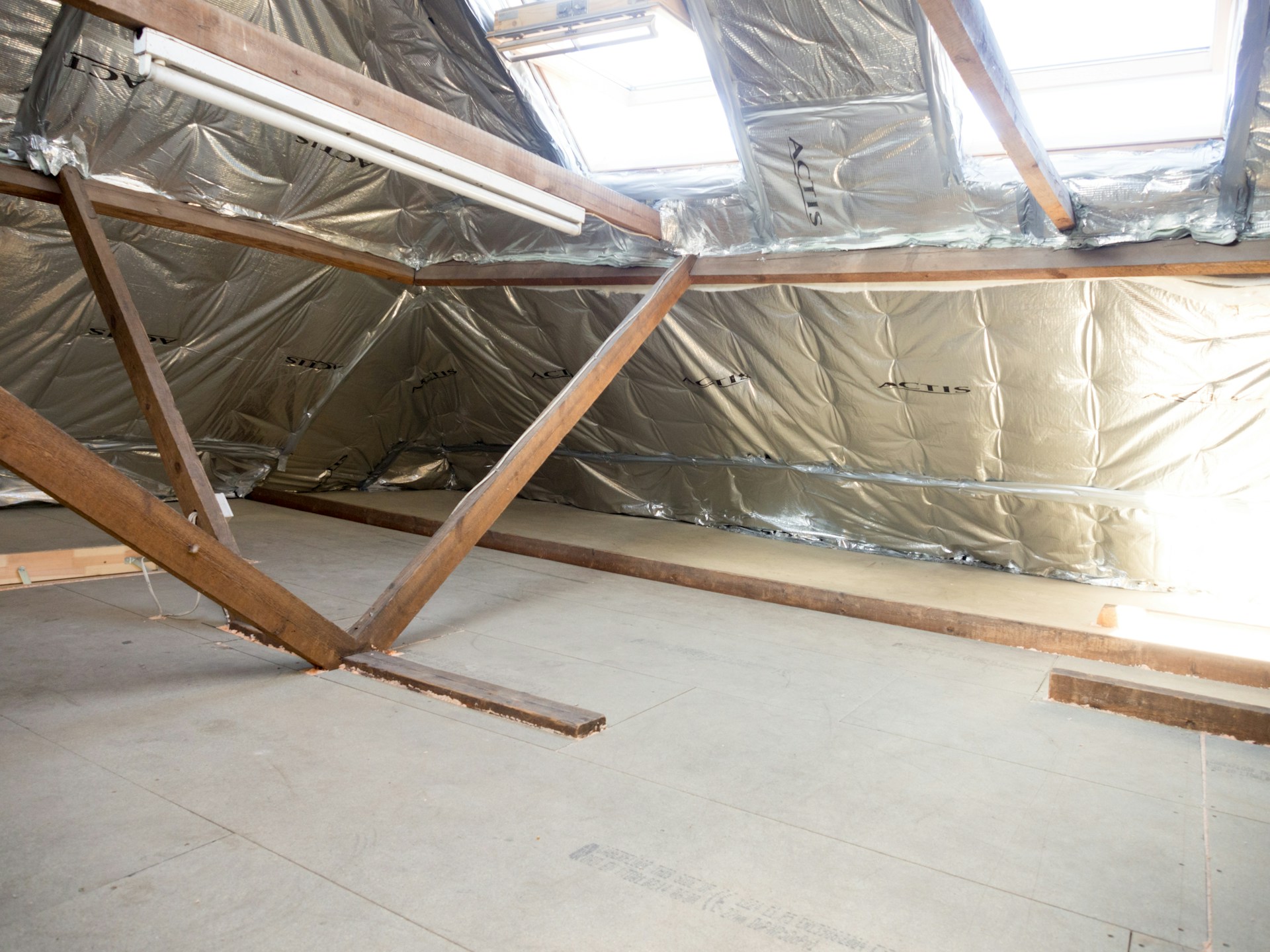 Insulated attic space with wooden beams and skylights.