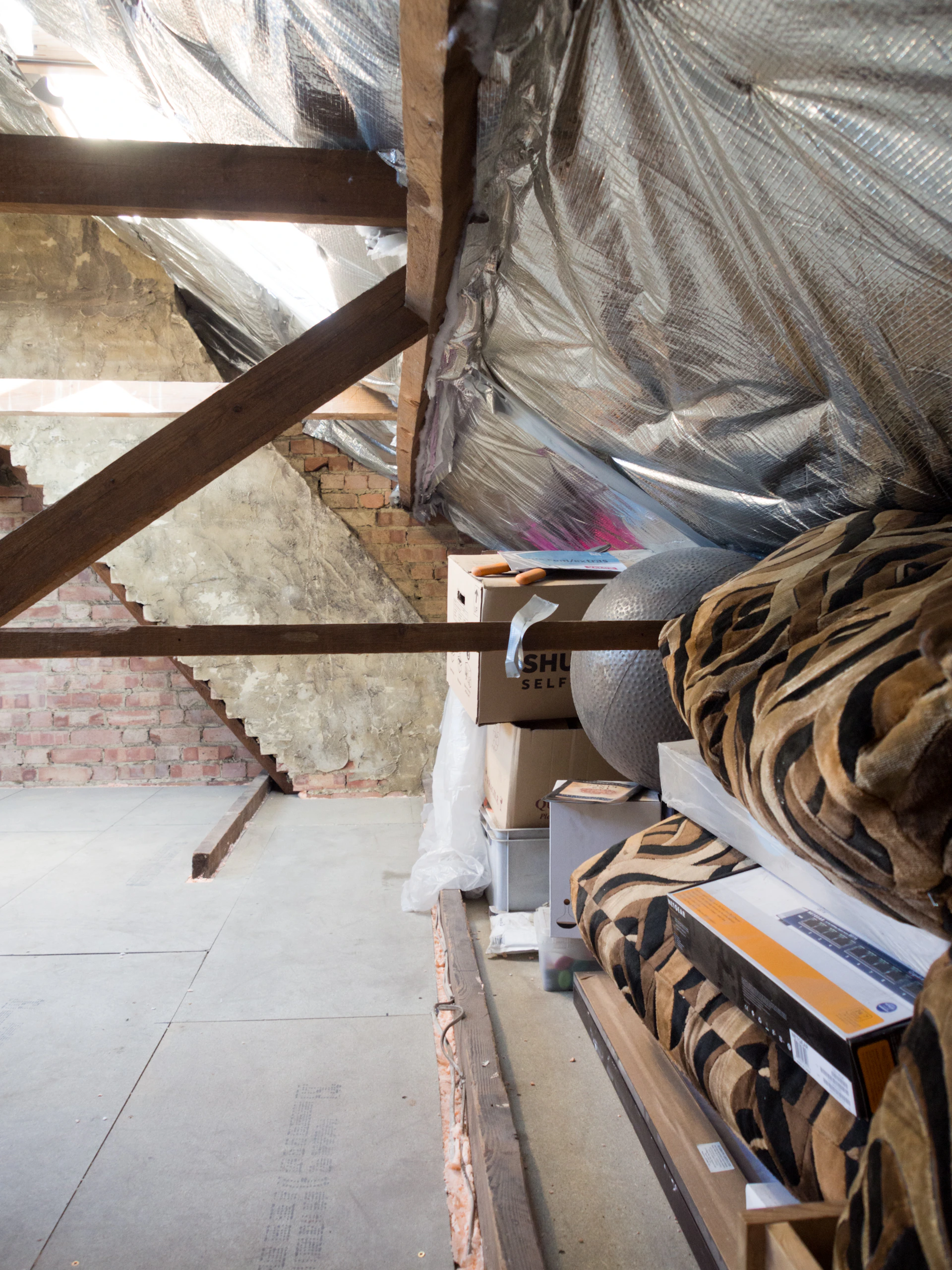 An attic filled with boxes, insulation, and beams.