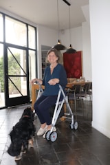 Woman uses a walker with her dog nearby.