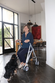 Woman uses a walker with her dog nearby.