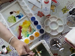 Someone is painting with watercolor paints on a table.
