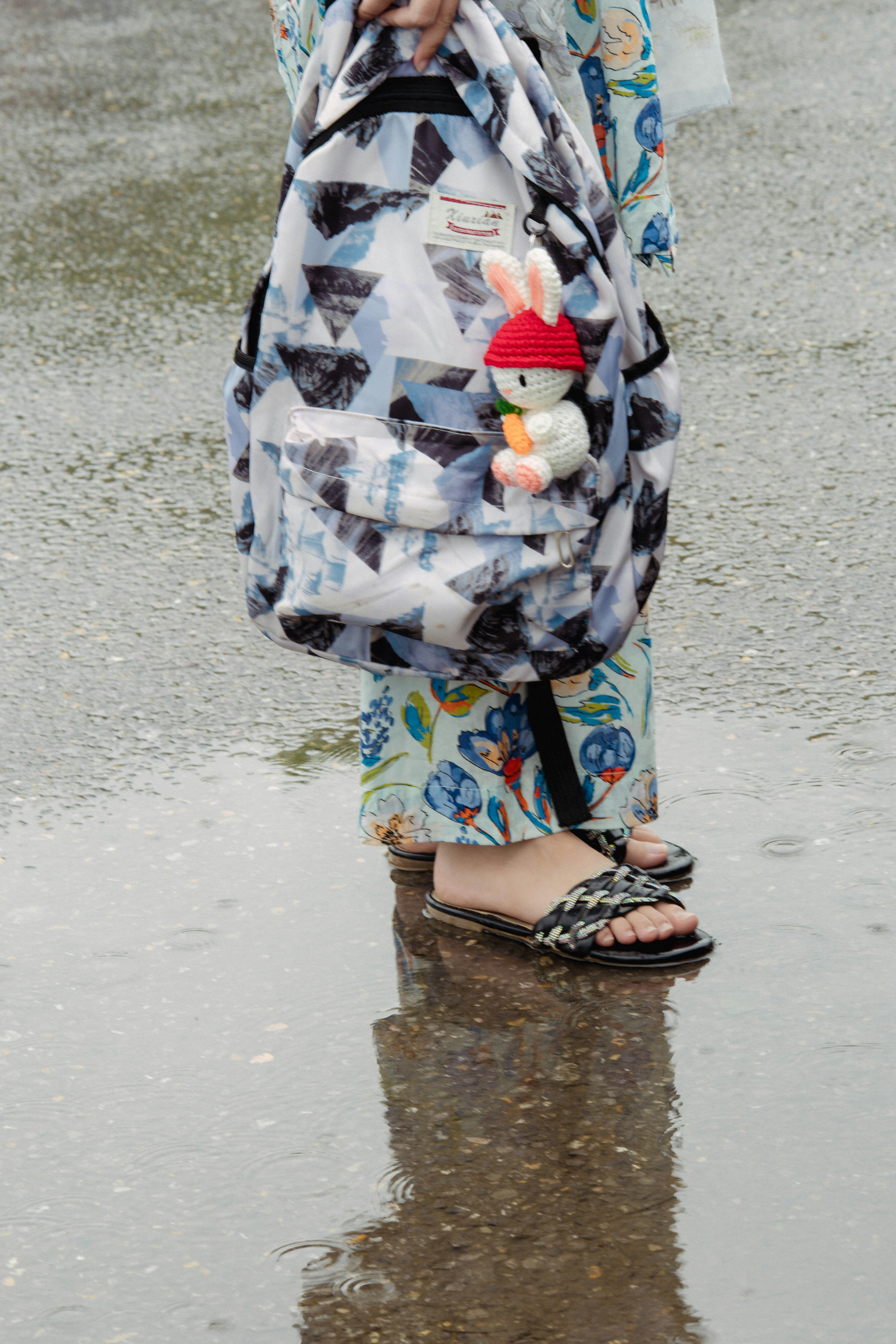 Person with a backpack standing in a puddle.