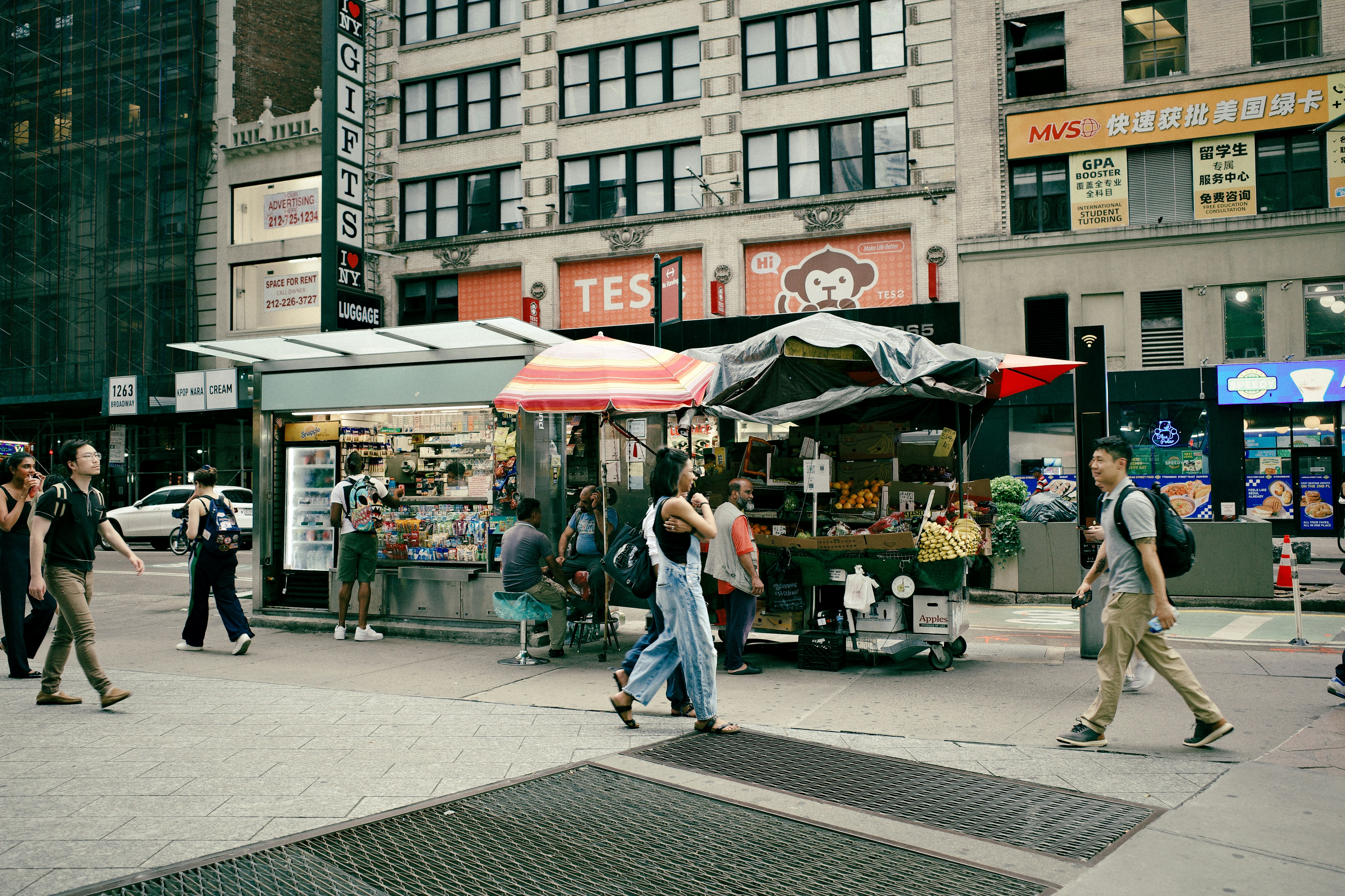 People walk past food carts on a city street.