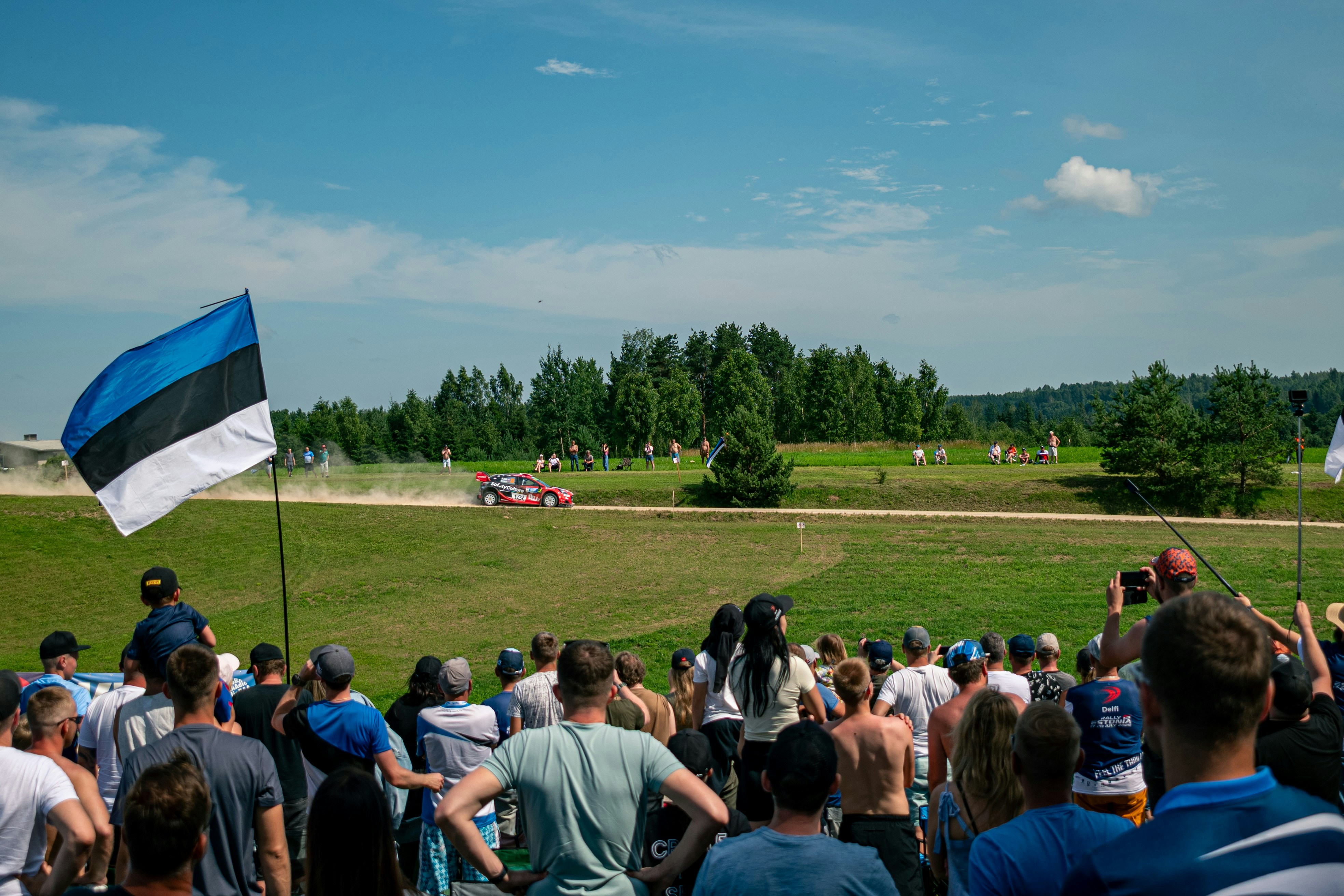 Ein Rallye-Auto rast an Zuschauern vorbei.