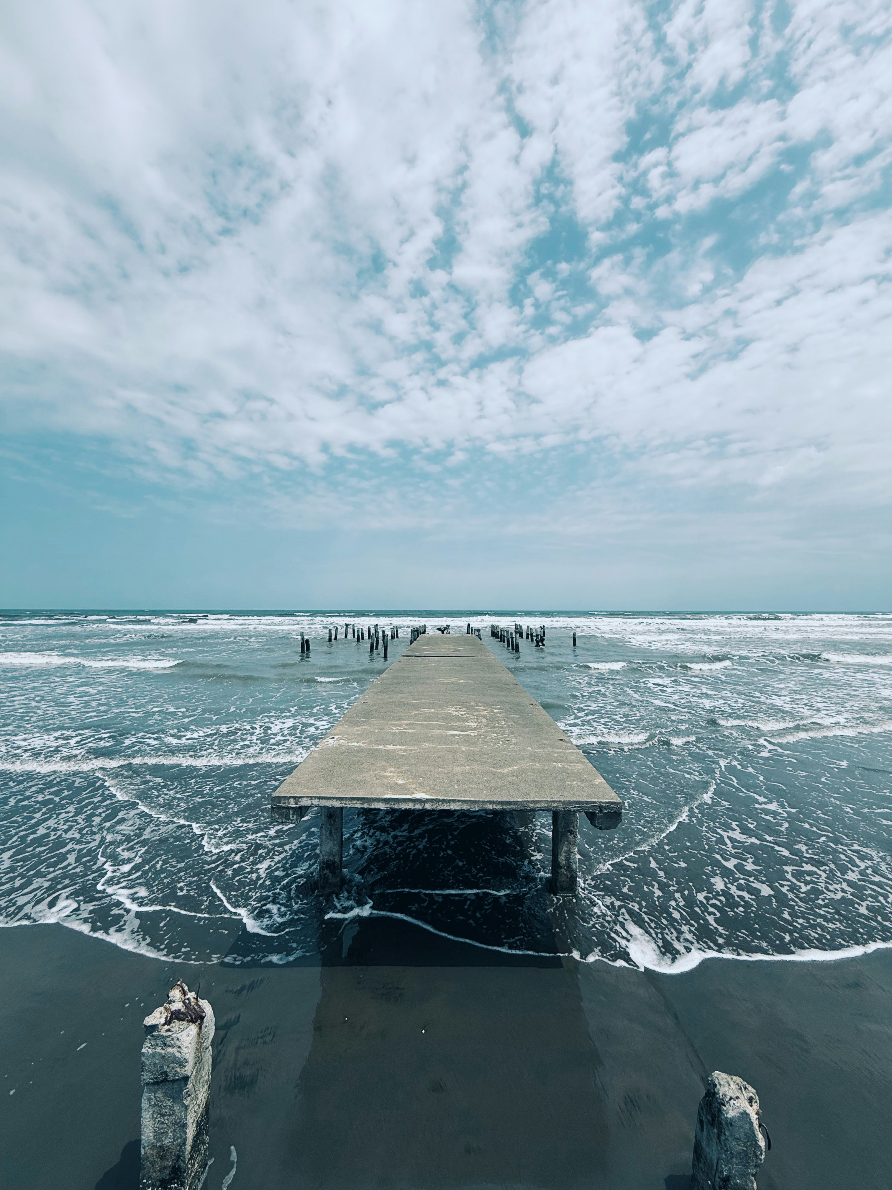 Un muelle se extiende hacia el océano bajo un cielo nublado.