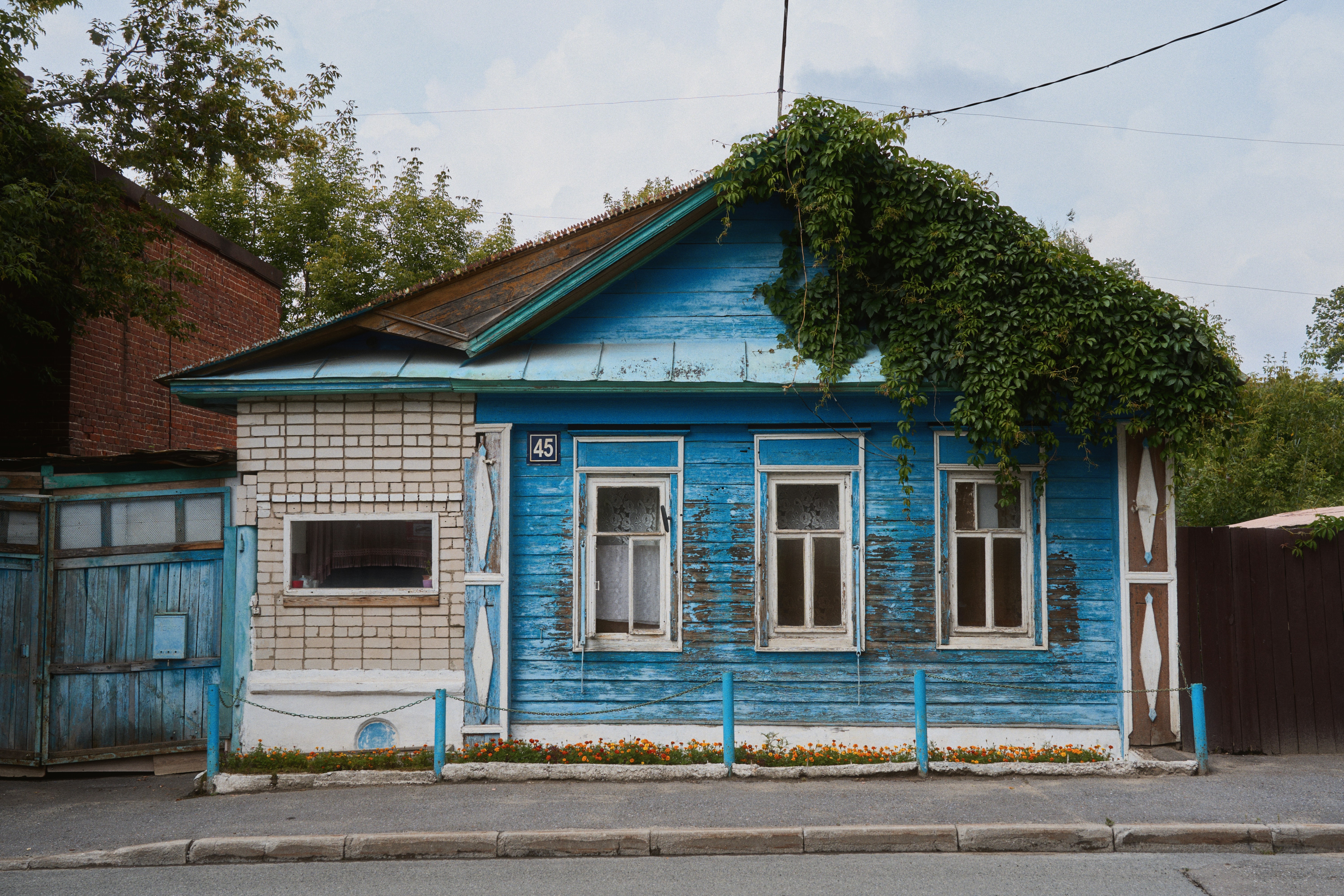 A weathered blue house with ivy growing.