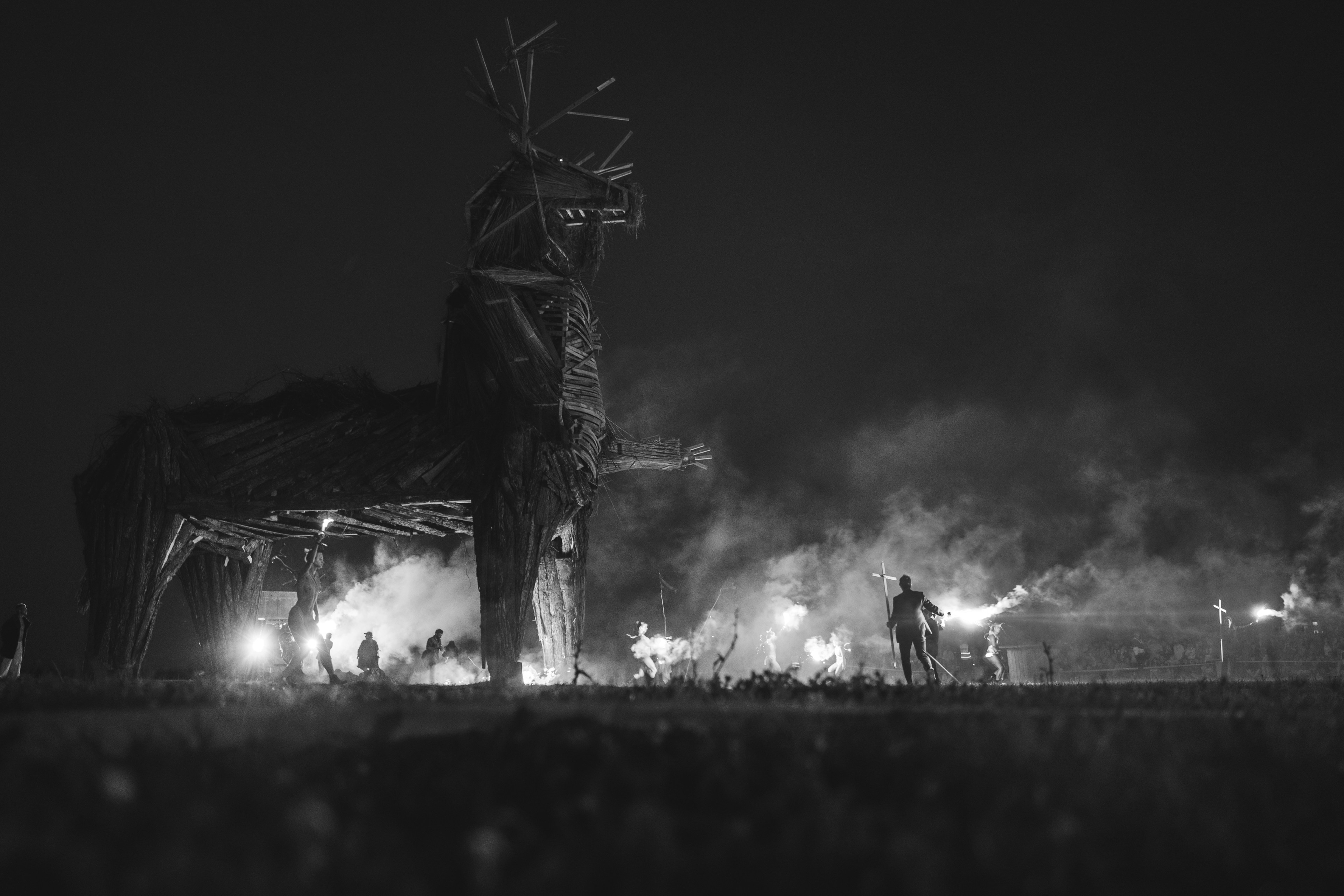 People gather around a large wooden horse structure.