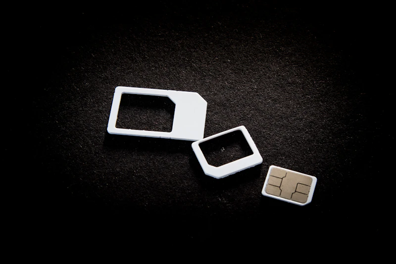 A SIM card and two card adaptors on a black surface