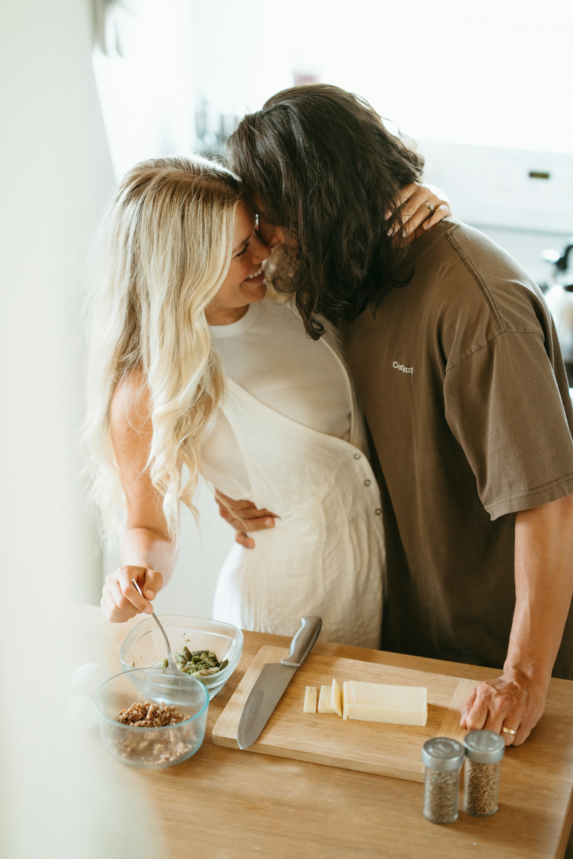 A couple lovingly prepares food together in the kitchen.