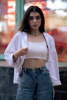 Woman poses wearing a white shirt and jeans.
