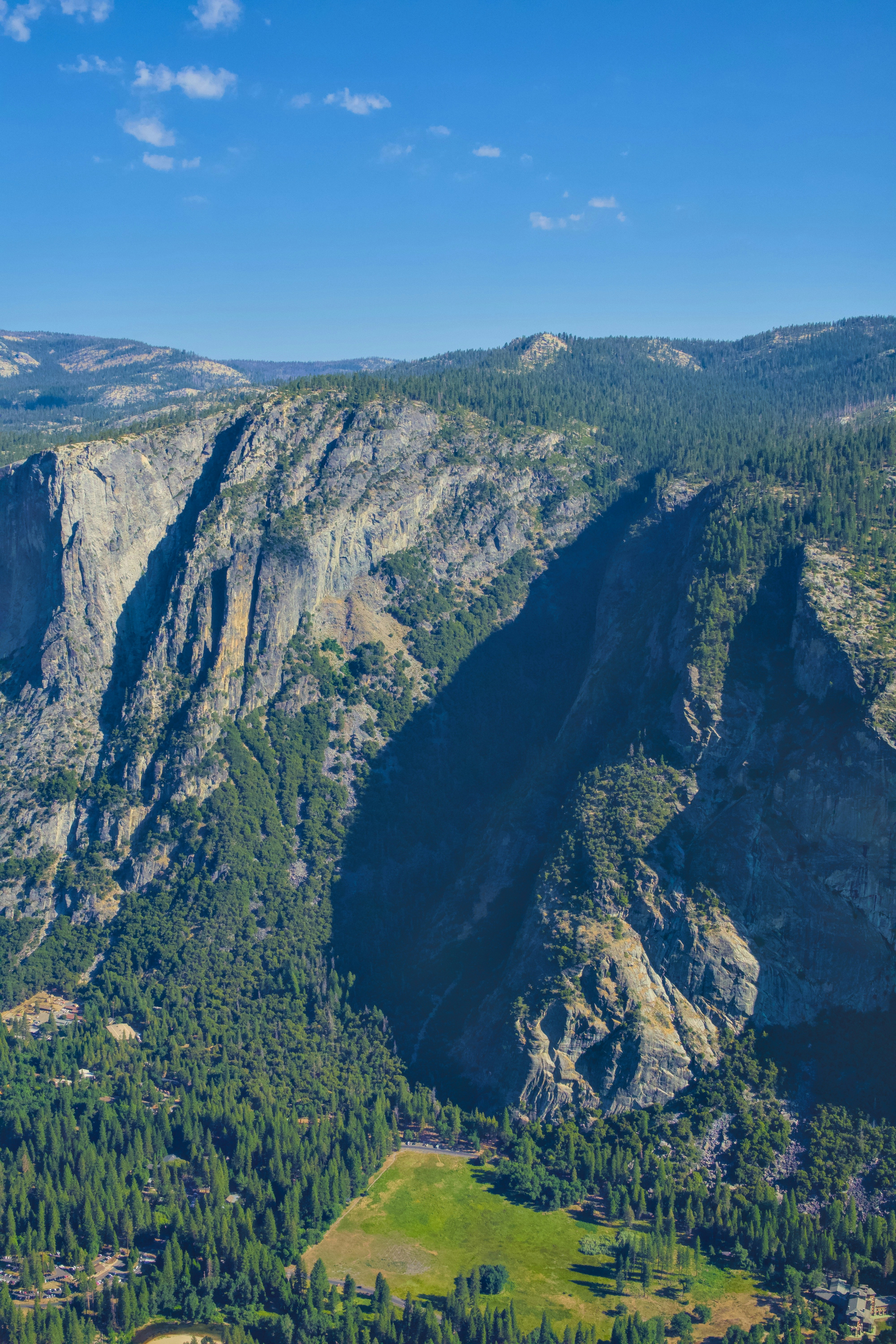Majestic mountains and lush forest under a blue sky.