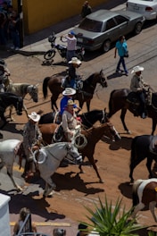 Cowboys on horseback ride through a city street.