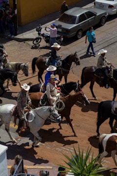 Cowboys on horseback ride through a city street.