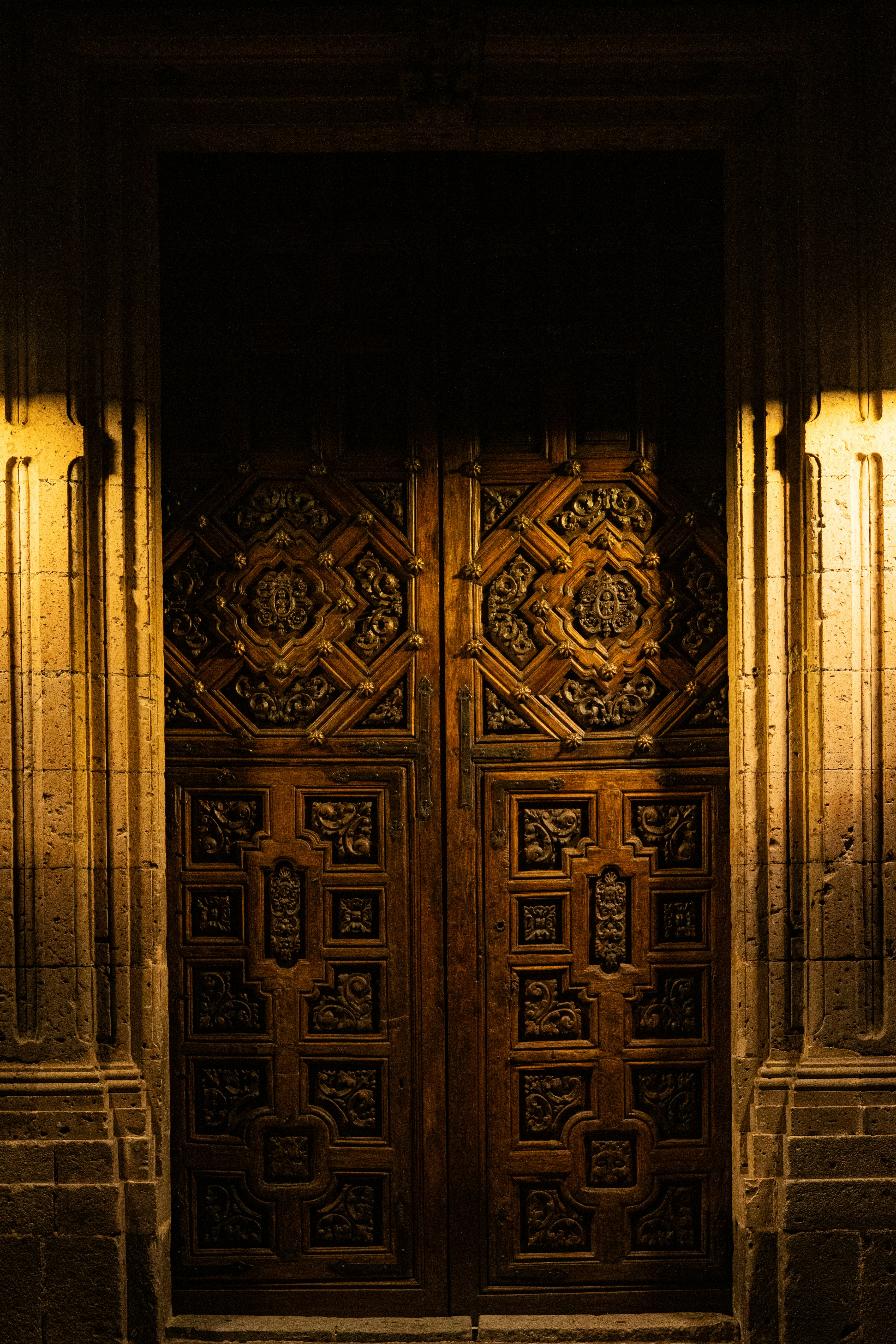 Verzierte Holztüren leuchten in der Dunkelheit.