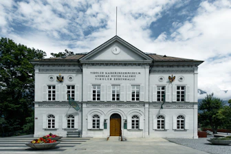 A stately white building stands under a cloudy sky.