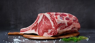 A large raw ribeye steak on a wooden board.