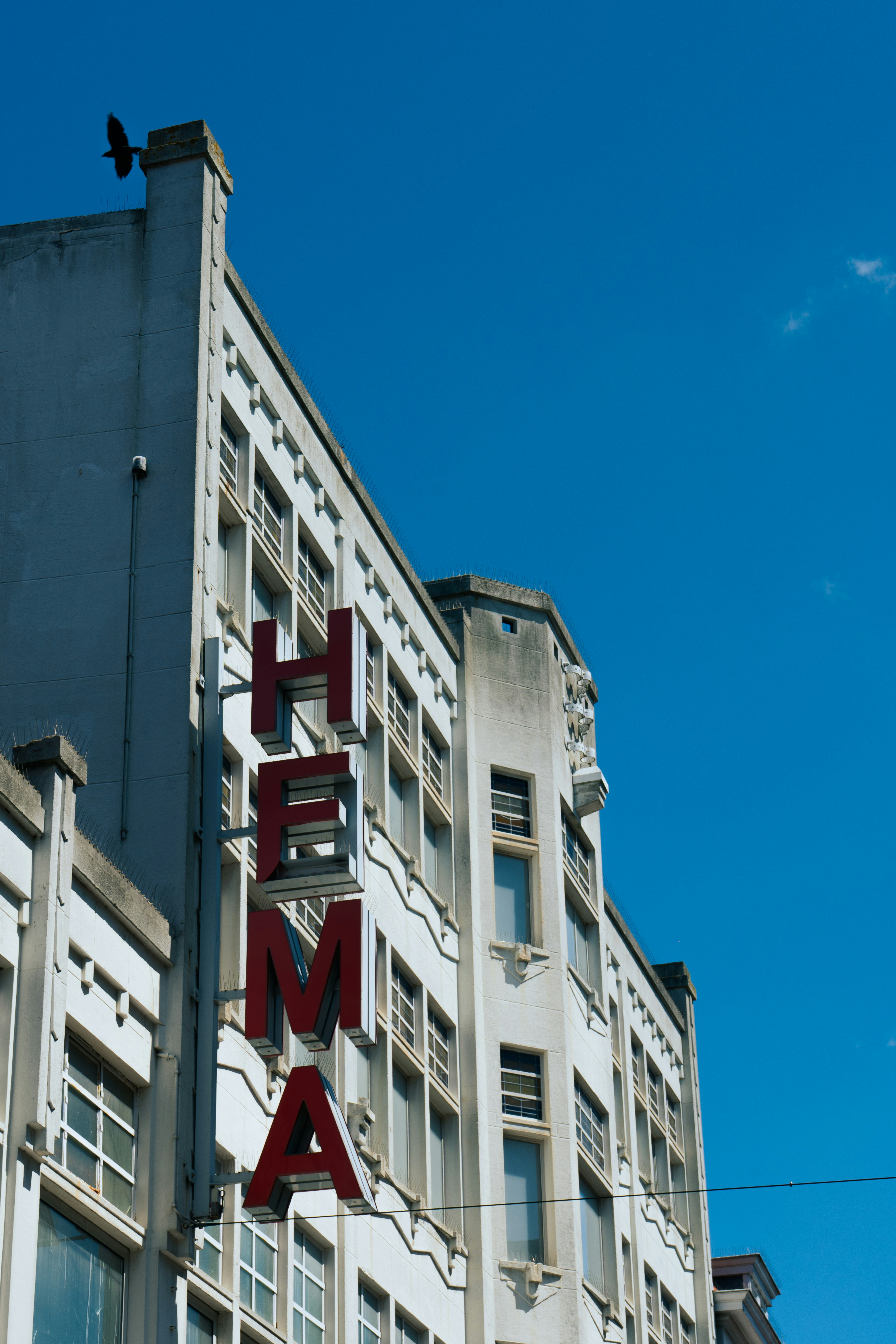 Hema store sign against a bright blue sky.