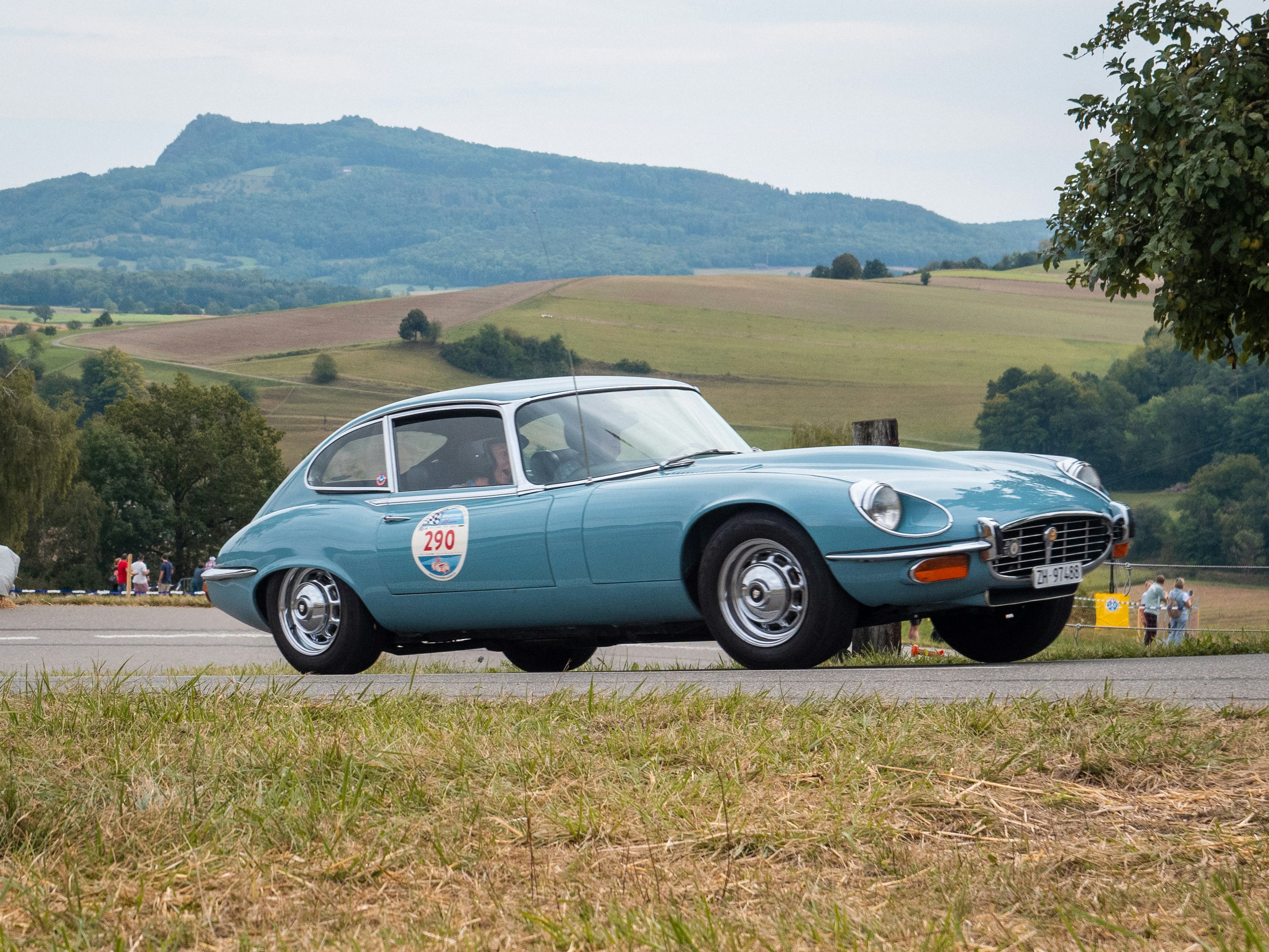 A classic blue jaguar car is seen outdoors.