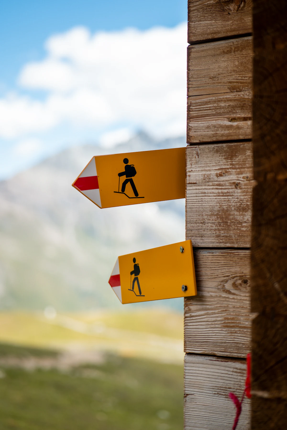 Yellow hiking signposts on a wooden post near Zinal