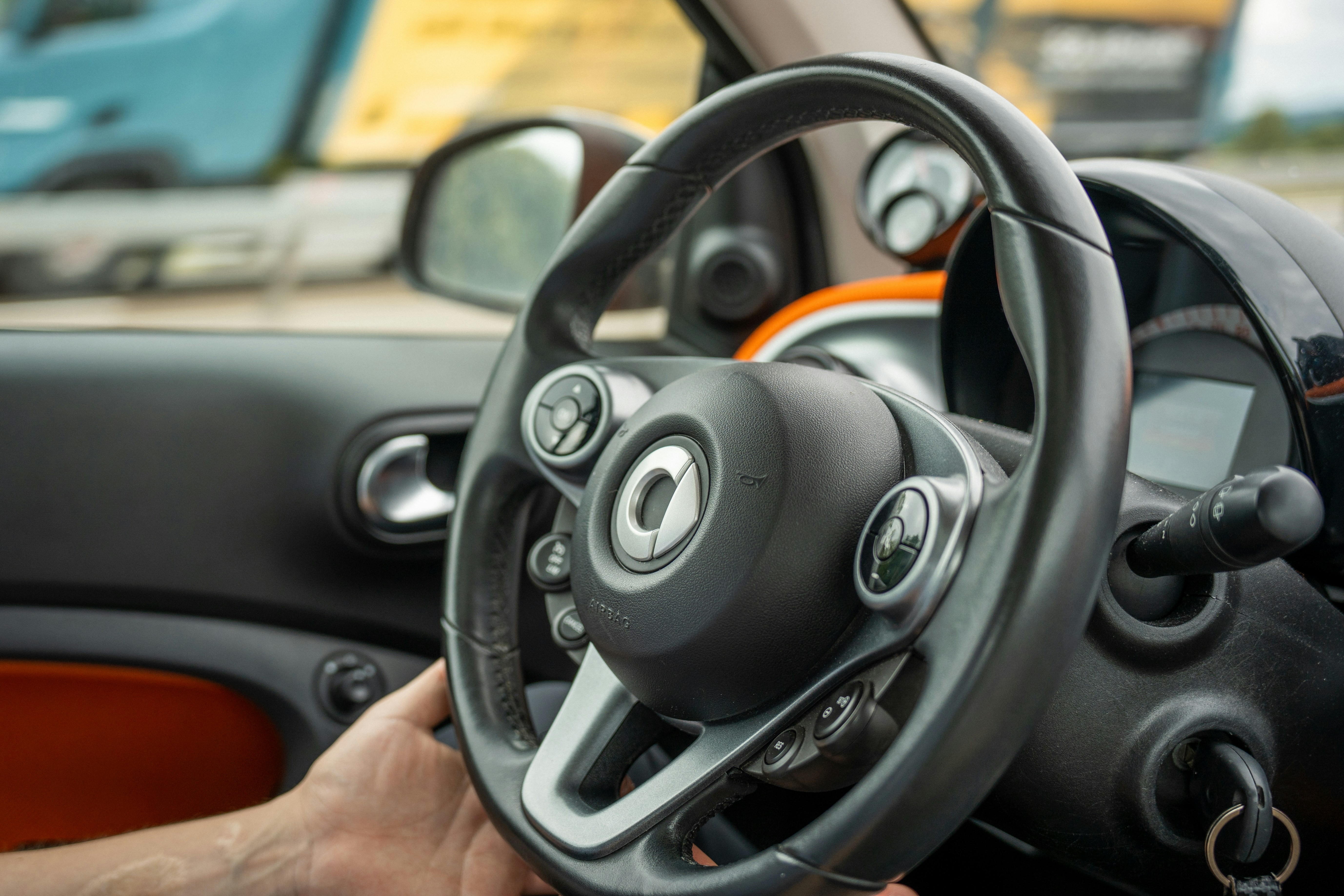 A hand holds the steering wheel of a car.