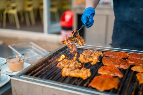 A cook grills chicken on a barbecue.