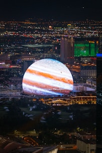 Jupiter projects over a cityscape at night.