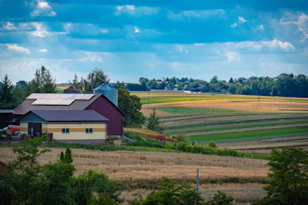 Farm buildings sit among fields under a blue sky.