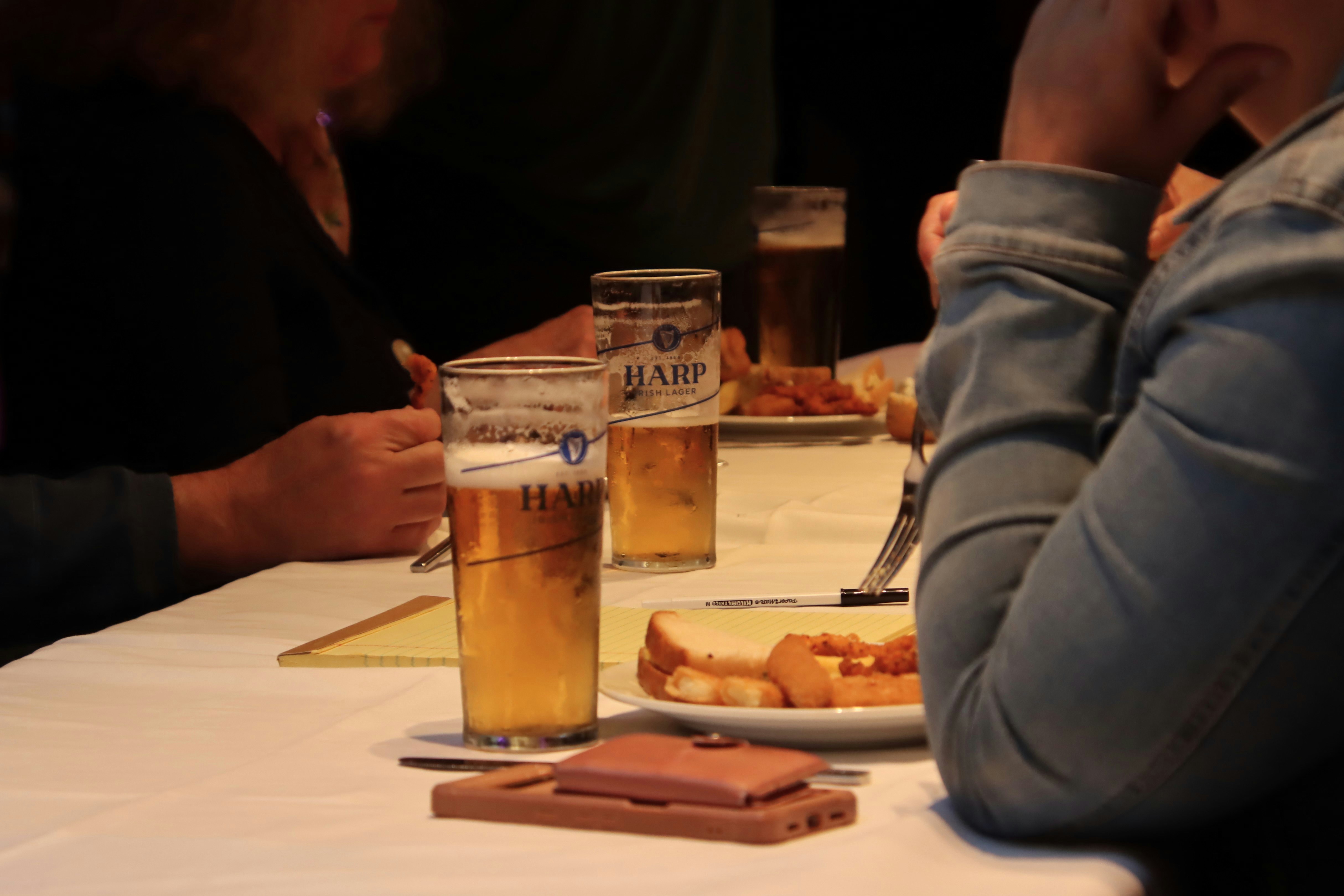 People drink beer and eat food at a table.
