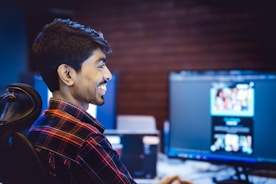 A man smiles while working on a computer.