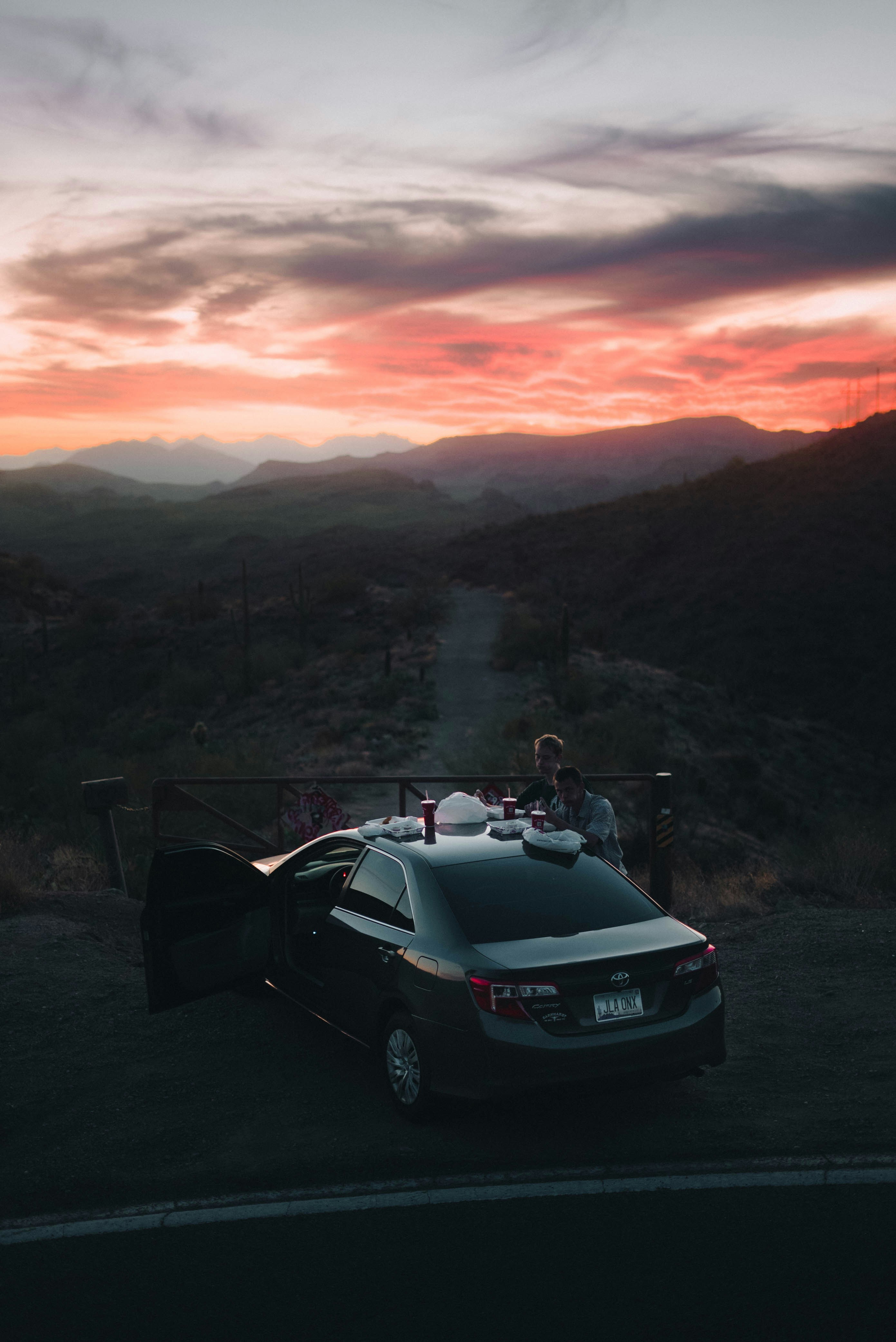 Couple enjoying a sunset picnic by their car.