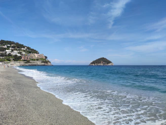 Beach with clear water and a sunny blue sky.