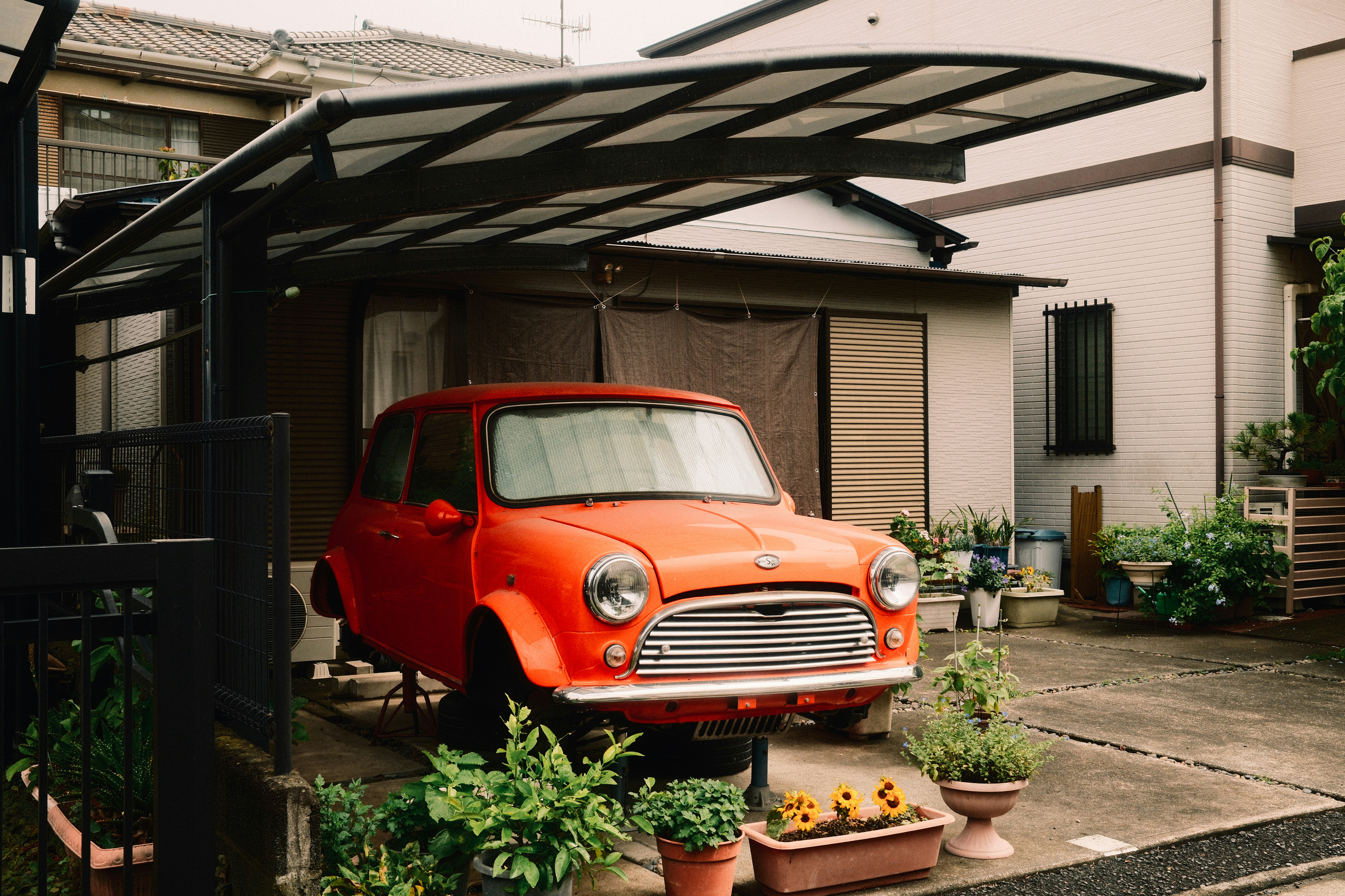 An orange mini car parked outside a house.