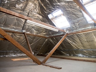 Attic interior with insulation and a skylight.