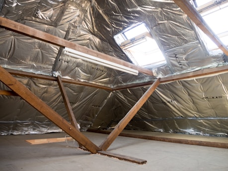 Attic interior with insulation and a skylight.