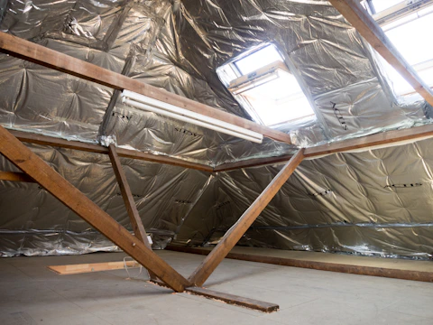 Attic interior with insulation and a skylight.