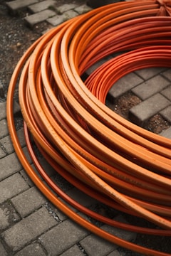 Orange tubes coiled on a brick pavement.