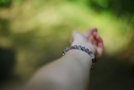 A hand with a bracelet reaches out.