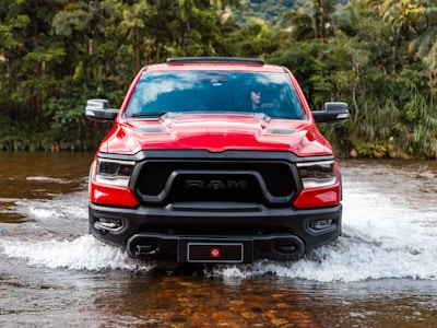 A red ram truck drives through water.