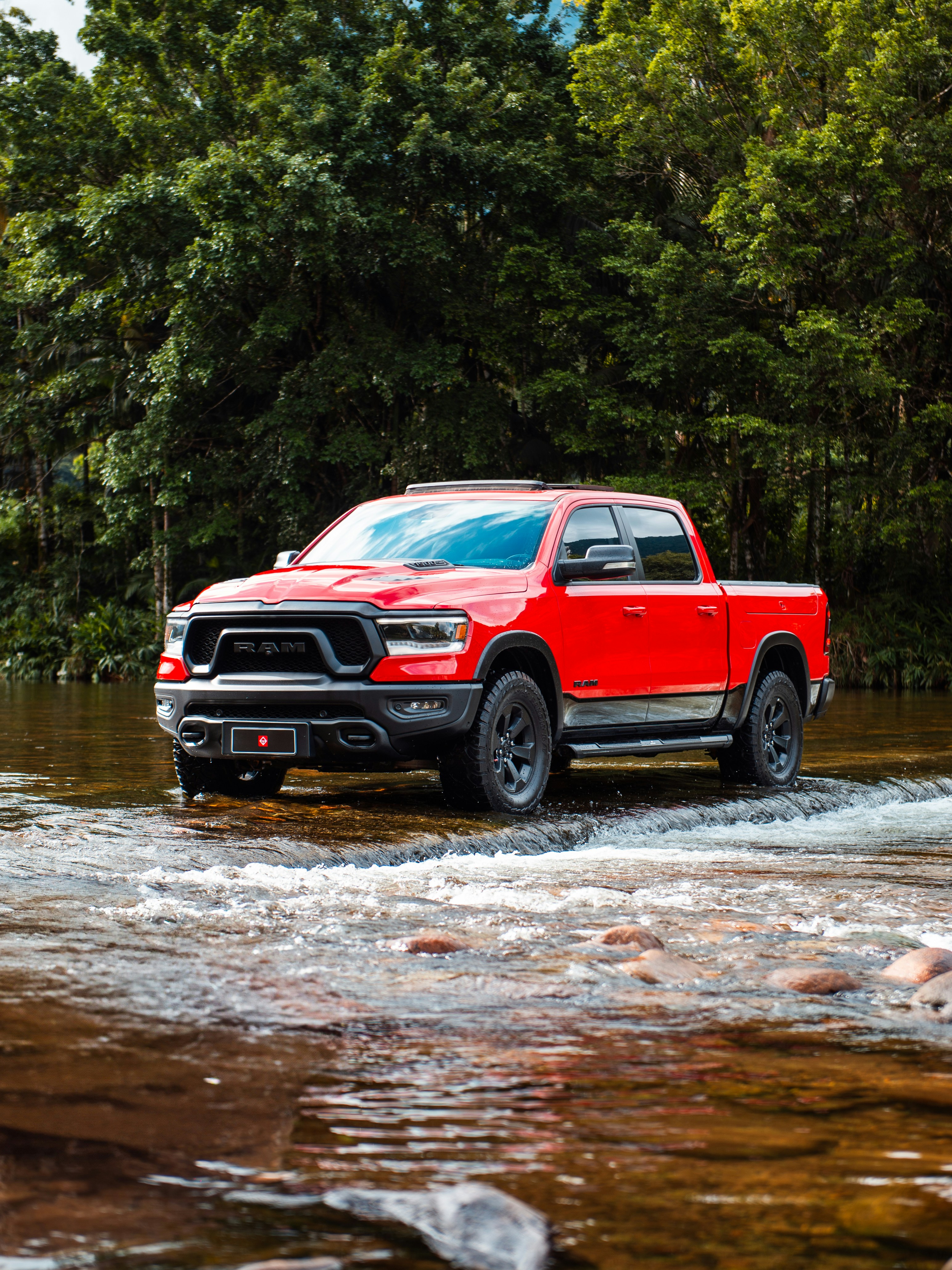 A red truck drives through the water.