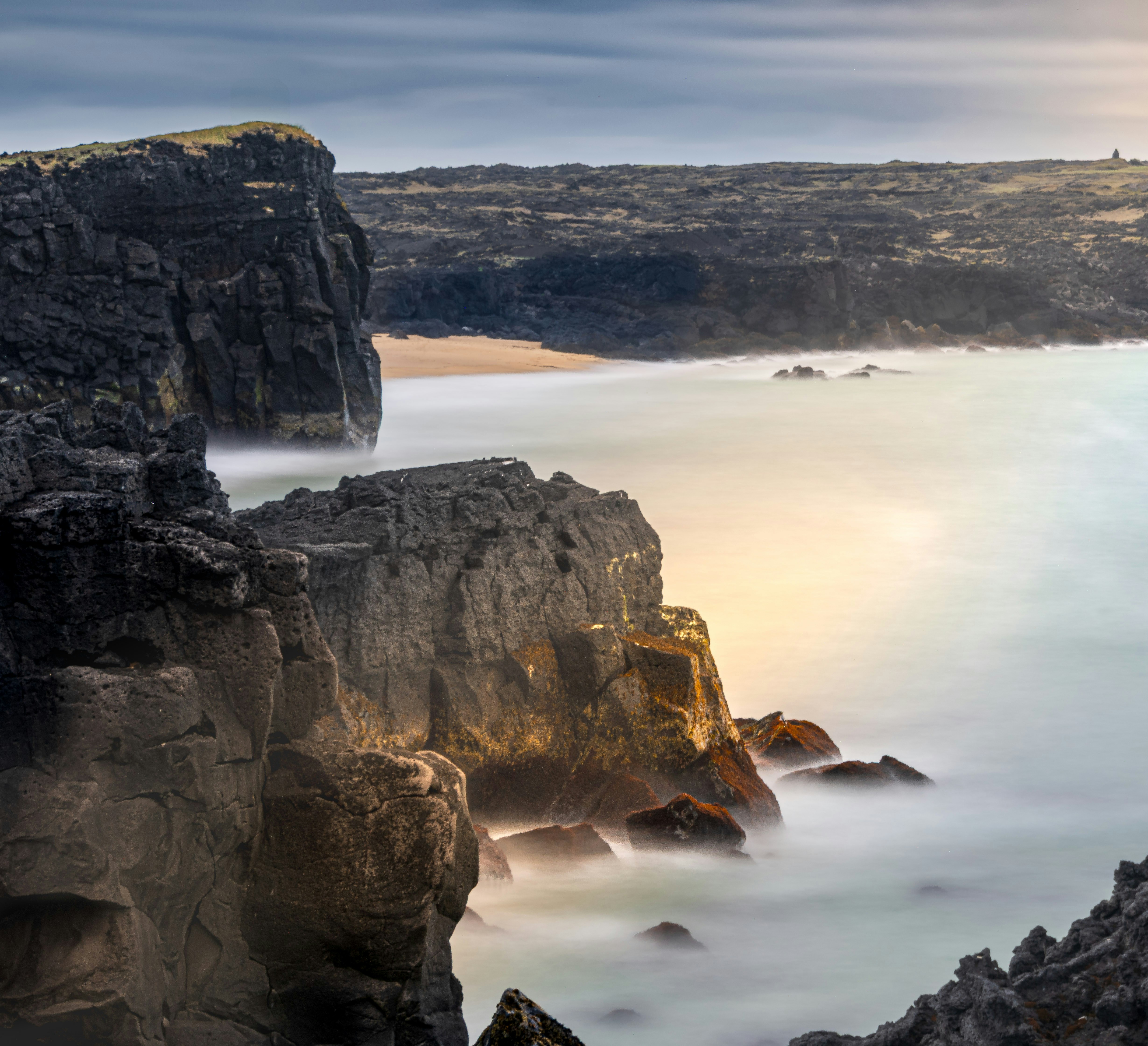 Rocky cliffs meet the ocean in the evening.