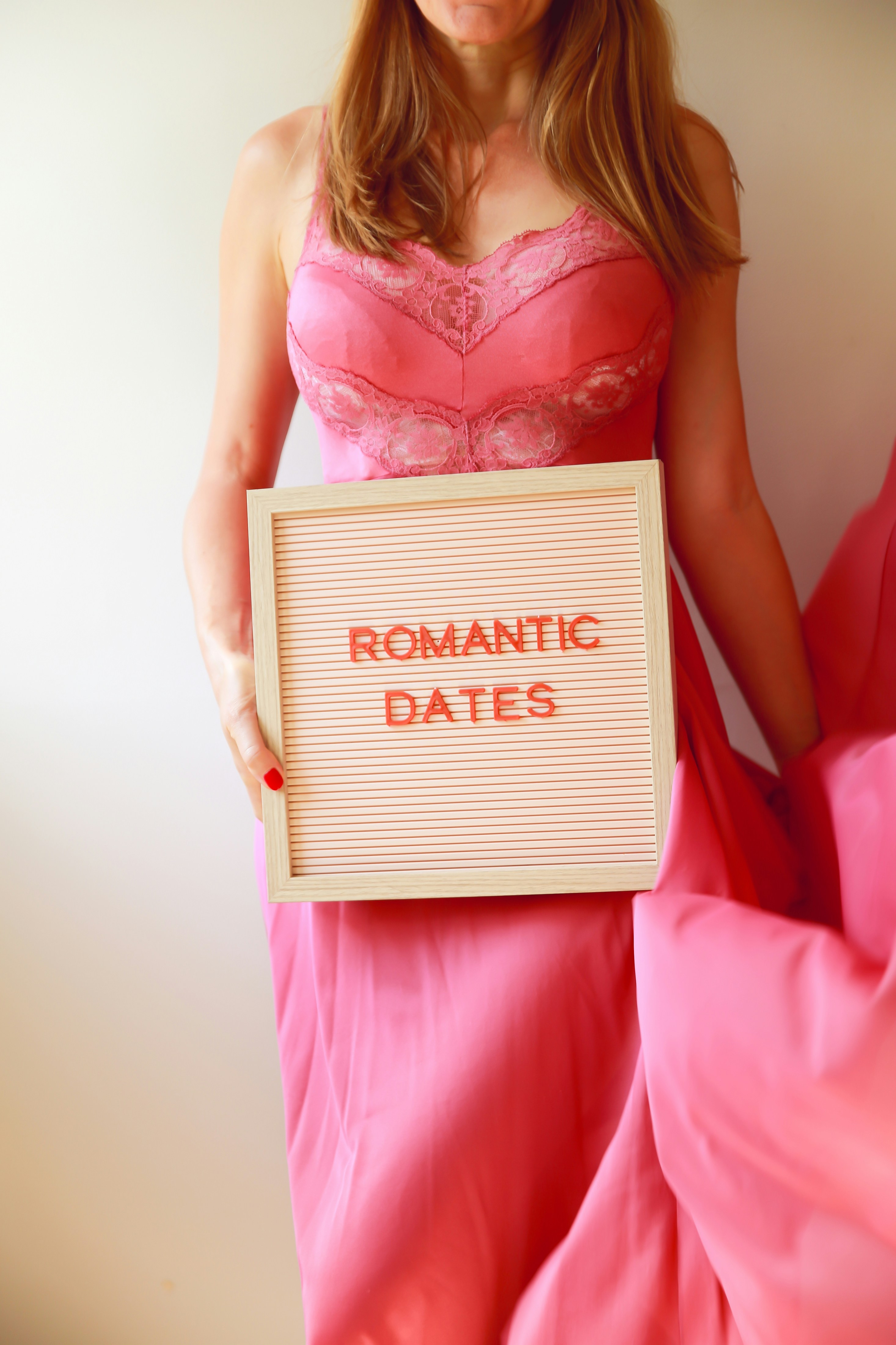 Woman in pink dress holds "romantic dates" sign.