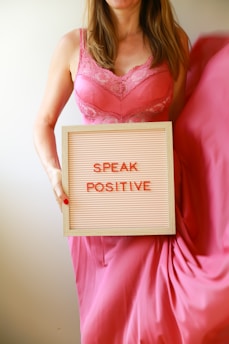 A woman holds a sign, "speak positive."