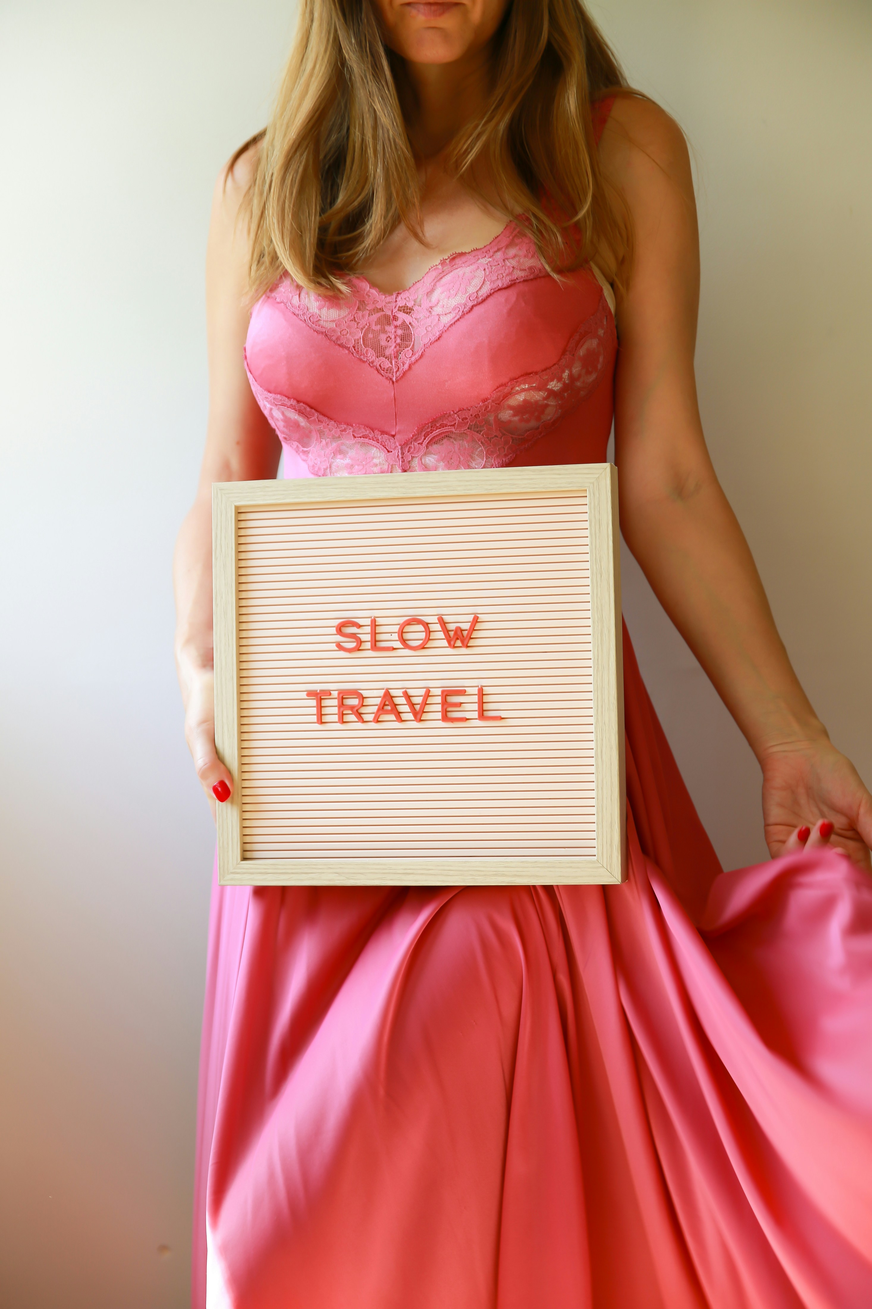 Woman holds a sign that says "slow travel."